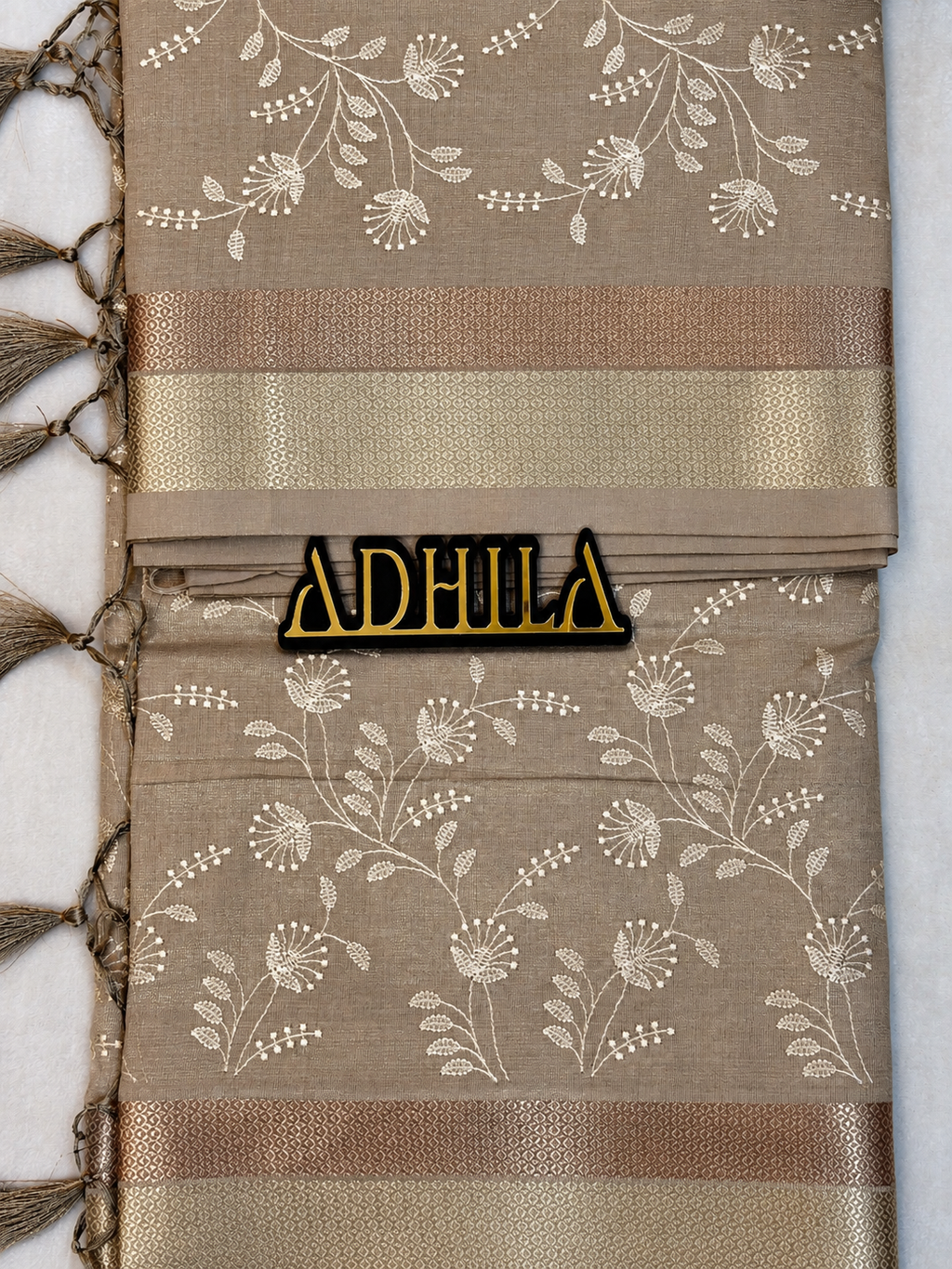 Grey Floral Tissue Saree – unfolded view showing zari border and Adhila logo