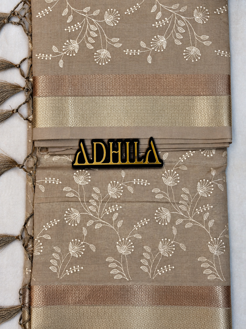 Grey Floral Tissue Saree – unfolded view showing zari border and Adhila logo